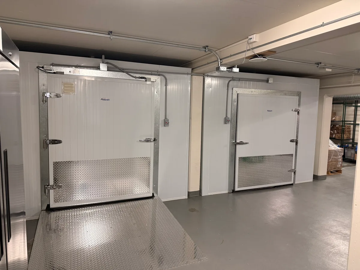 Two walk-in boxes side by side with diamond plate kick plates, one with a ramp up to its door