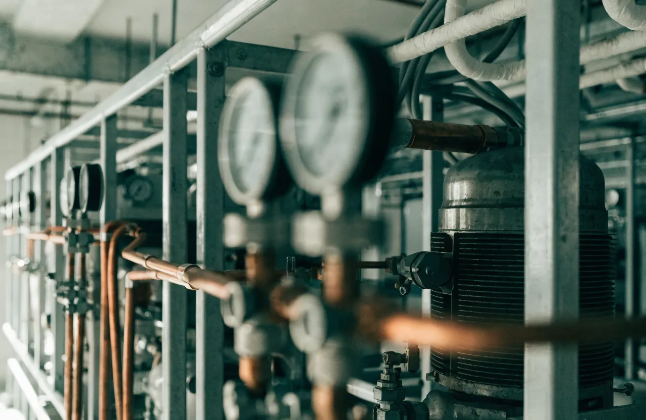 A commercial refrigeration rack: compressors, pressure gauges and insulated suction lines on a steel frame